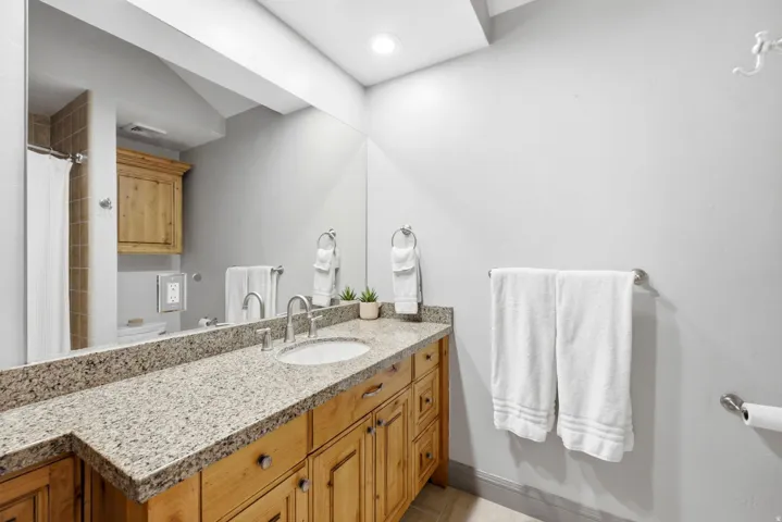 Vanity with an integrated sink, polished chrome faucet, and stone countertop
