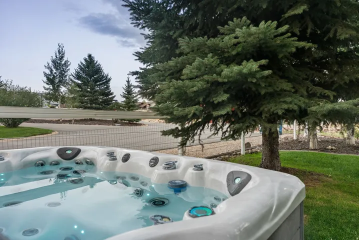 Outdoor spa with integrated lighting, surrounded by mature trees and manicured lawn