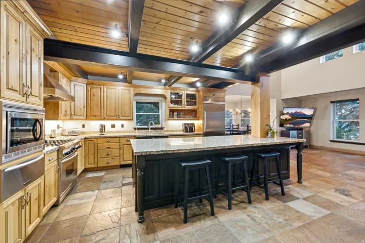 Kitchen featuring a large island, stainless steel appliances, wood cabinetry, and a wood plank ceiling with exposed beams