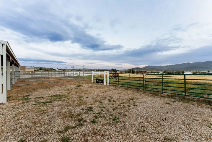 Expansive outdoor area featuring a gravel ground, green pasture beyond, and fencing