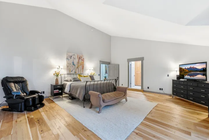 Vaulted ceiling, light wood-finish flooring, recessed lighting, and white walls