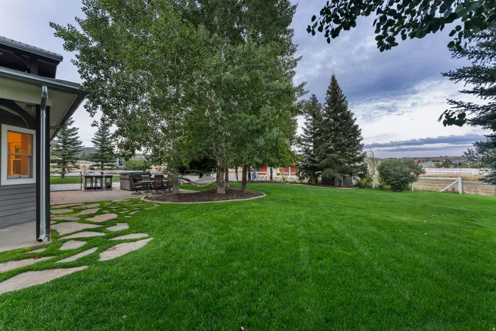 Expansive lawn with mature trees and a flagstone pathway leading to a paved patio area