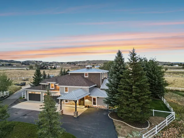 Expansive exterior with multi-level roofing, covered entryway, attached garage, and surrounding mature landscaping