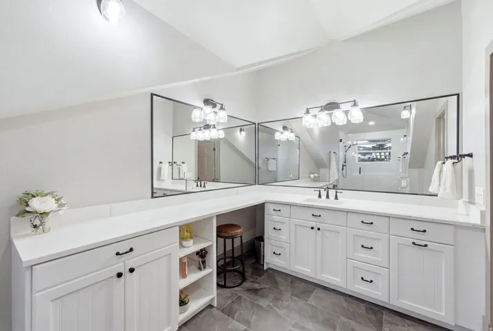 Dual vanity with undermount sinks, white cabinetry, and a full-width mirror