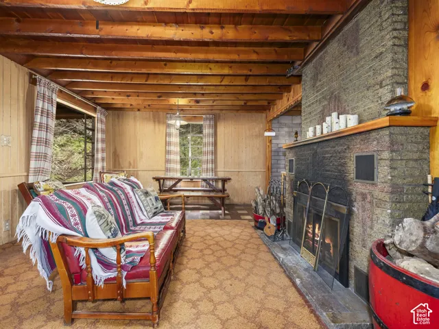 Exposed wood beam ceiling with wood paneling, featuring a brick fireplace with a stone hearth