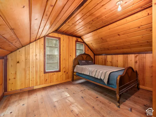 Wood-paneled walls and ceiling, two multi-pane windows, and wood flooring