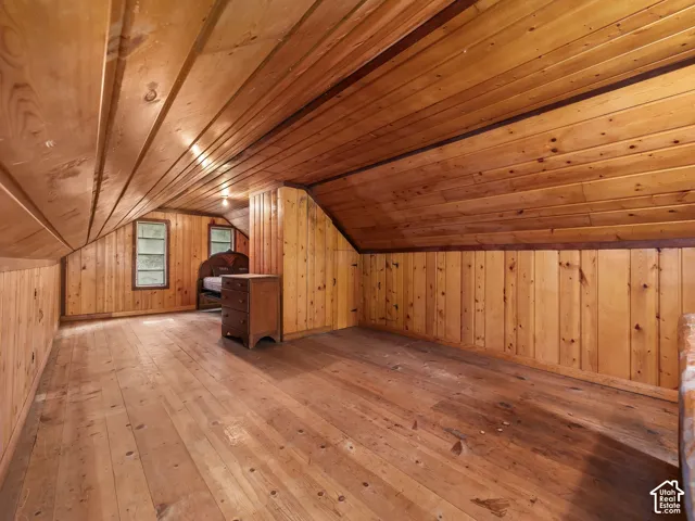 Wood-paneled walls and ceiling, wood flooring, and two windows
