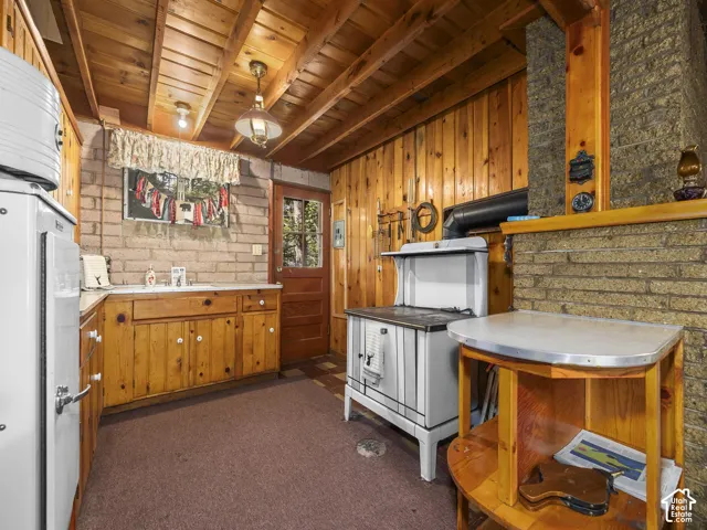 Wood-paneled walls and ceiling, brick-patterned wall, wood cabinetry, and a built-in stove