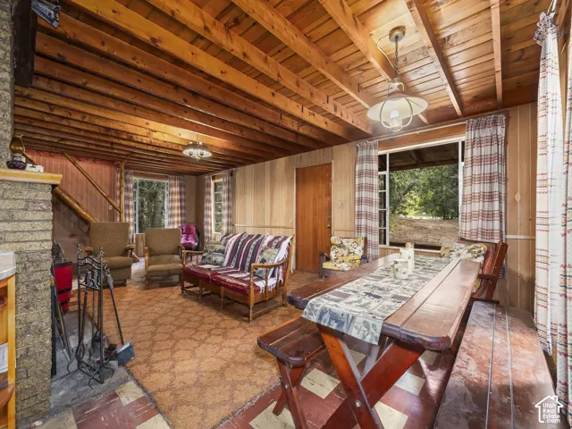 Exposed wood beam ceiling, wood plank walls, brick fireplace structure, and multiple windows