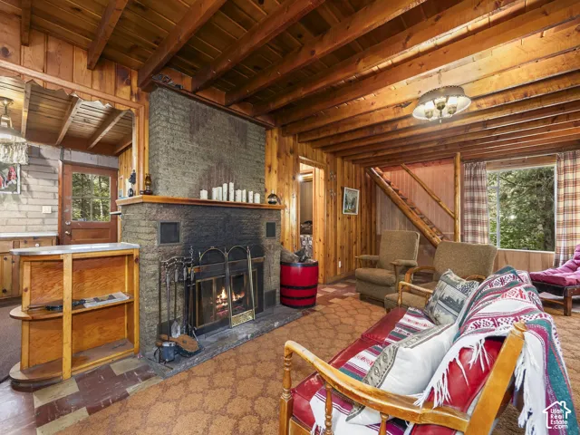 Exposed wood-beam ceilings, wood paneling, a stone fireplace, and a built-in staircase