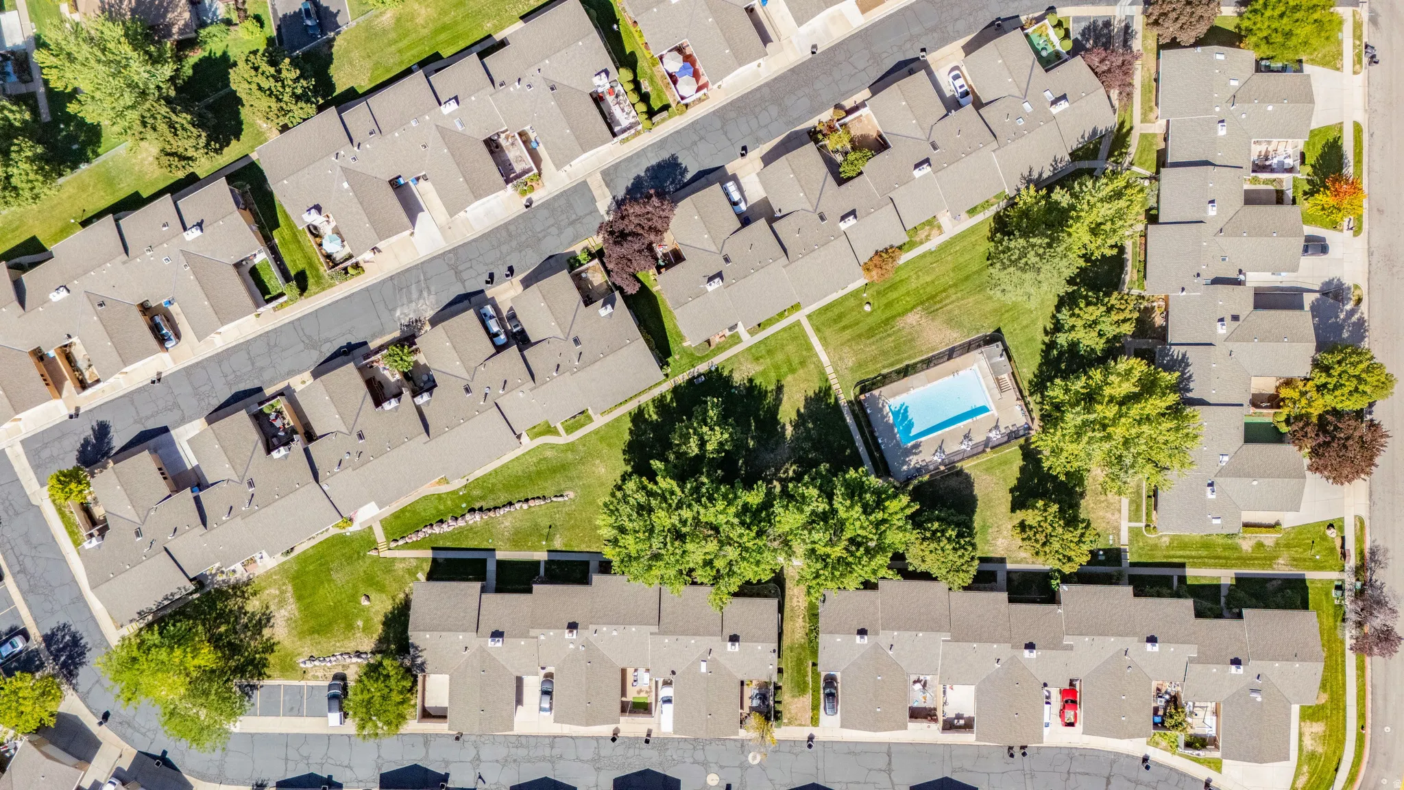 Aerial showing community amenities include a swimming pool, paved pathways, and mature landscaping