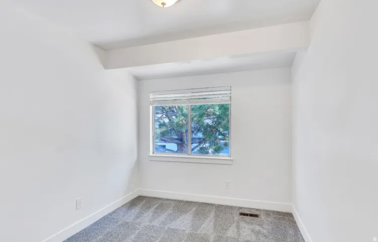 White walls, gray patterned carpet, and a window with blinds