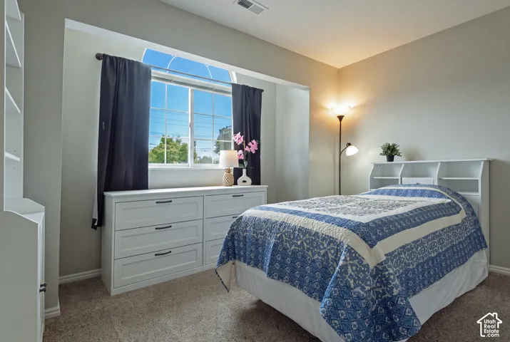 Arched window with grid panes, built-in shelving, plush carpet flooring, and a white built-in dresser