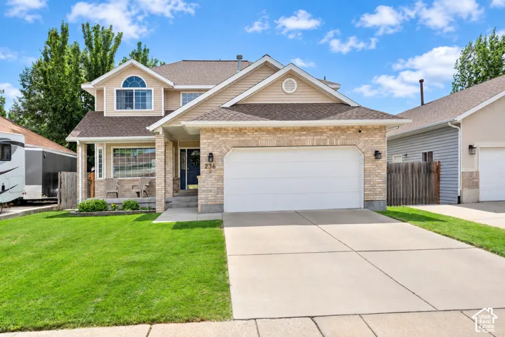 Two-story residence featuring a brick and siding exterior, an attached two-car garage, a concrete driveway, and a covered front porch