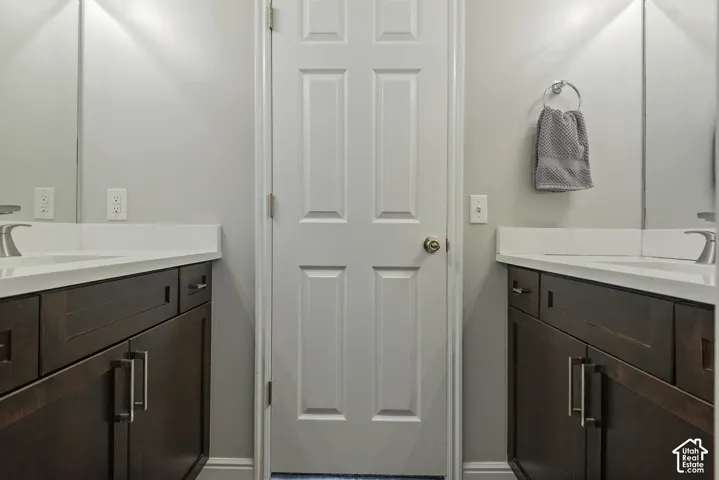 Dual vanity with dark wood-finish cabinetry, white countertops, and integrated rectangular sinks