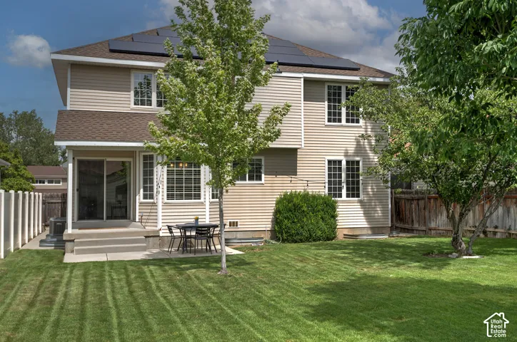 Expansive backyard with manicured lawn, established trees, and a concrete patio