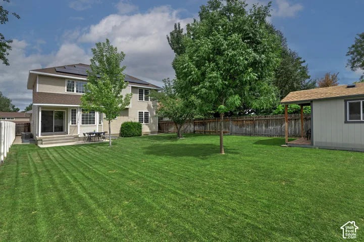 Expansive rear yard with mature trees, a detached storage shed, and a privacy fence