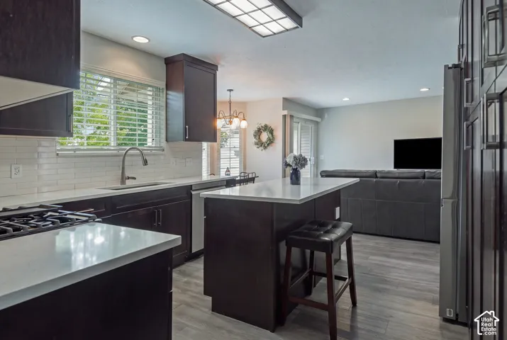 Kitchen featuring dark wood-finish cabinetry, light countertops, subway tile backsplash, and a central island with bar seating