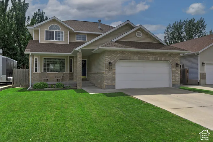 Two-story residence featuring a brick and siding exterior, front porch with stone pillars, and an attached two-car garage