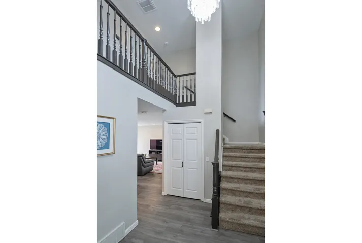 Two-story foyer with a chandelier, wood-finish flooring, and a carpeted staircase with dark wood railings