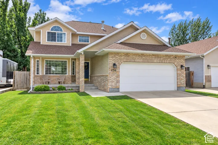 Brick and siding exterior with a concrete driveway, attached garage, and a covered front porch featuring stone accents