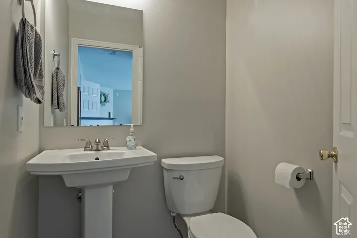 Pedestal sink with a polished chrome faucet, rectangular mirror, and neutral wall paint