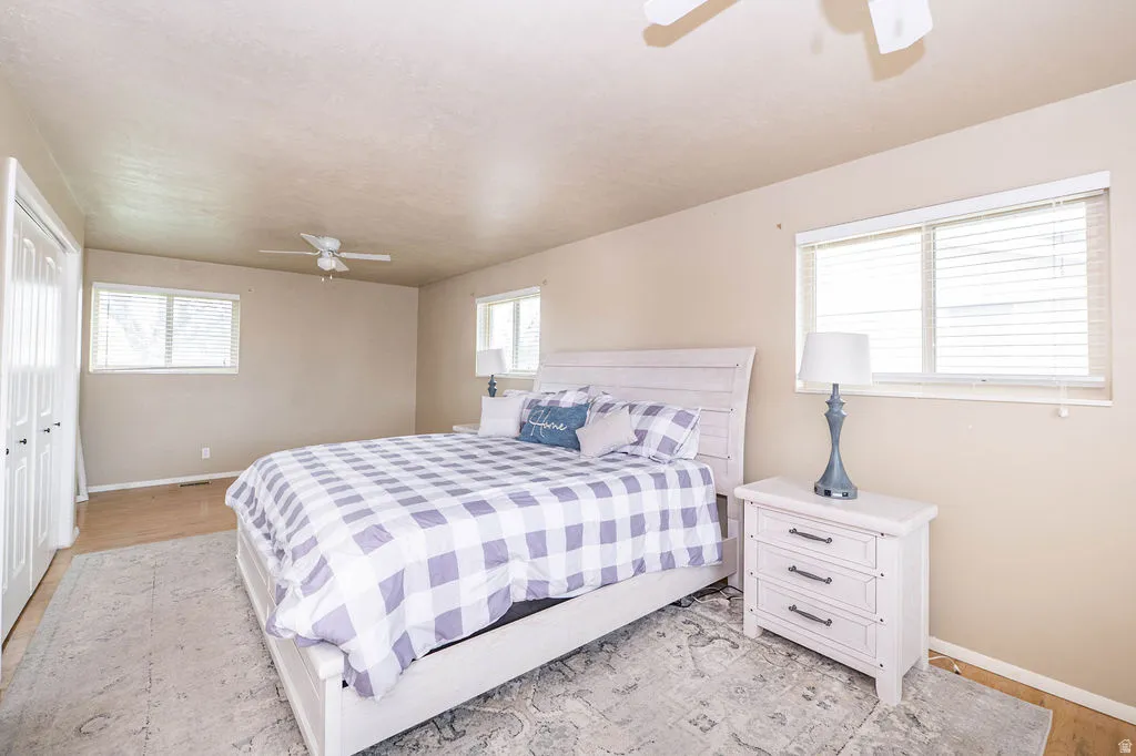 Recessed windows with blinds, wood-finish flooring, and a ceiling fan