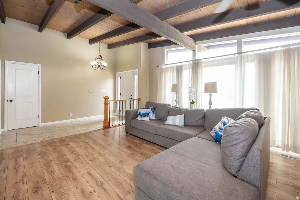 Vaulted wood-plank ceiling with exposed beams, wood-finish flooring, and large windows with transom panels