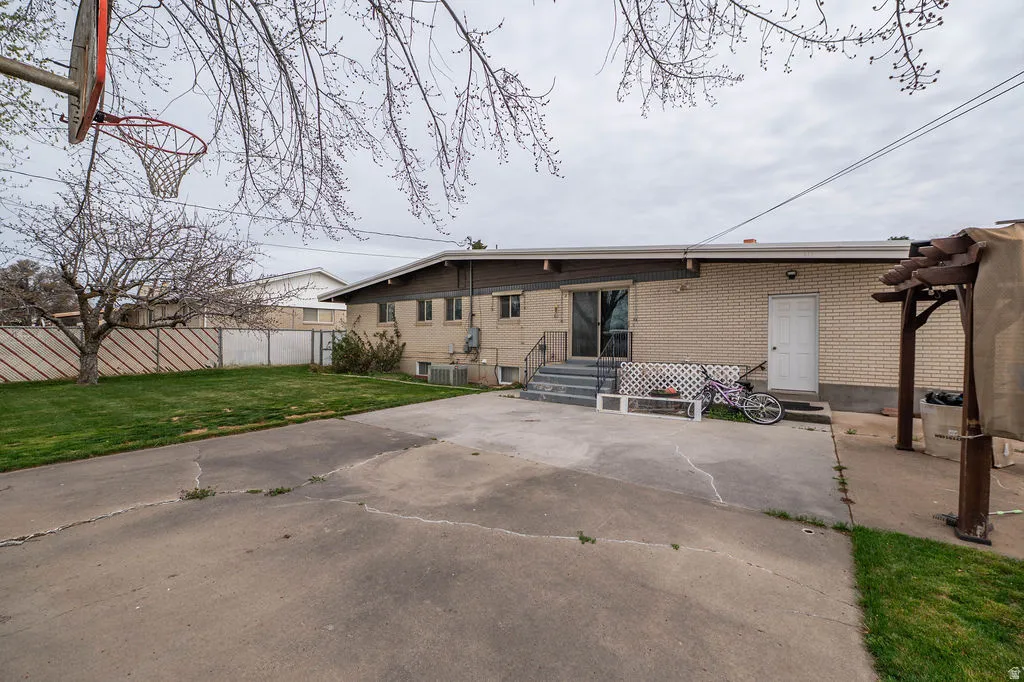 Expansive paved patio area, mature trees, and a basketball hoop