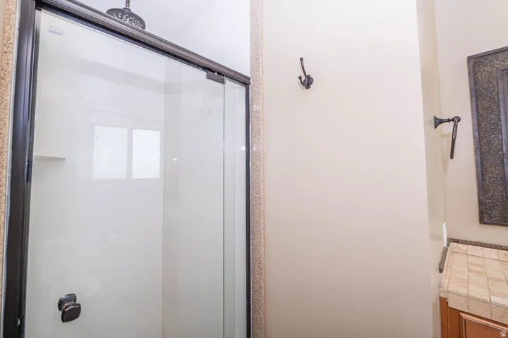 Shower enclosure with glass panels, dark bronze framing, and a rain showerhead