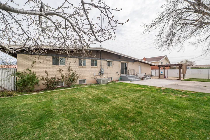 Expansive lawn area, brick exterior, concrete patio, and a wooden pergola structure