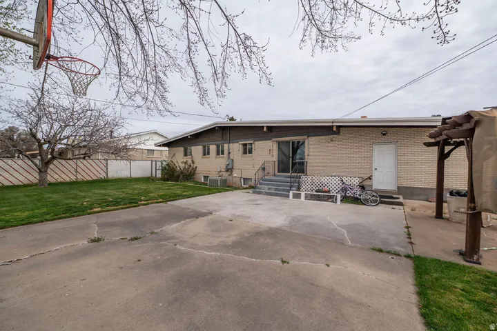 Expansive paved patio area, mature trees, and a basketball hoop