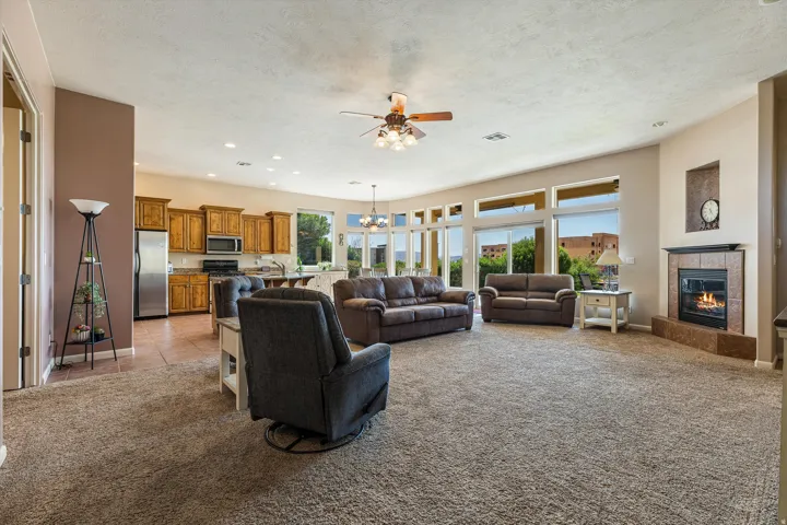 Open-concept living space with a gas fireplace, a ceiling fan, recessed lighting, and expansive windows