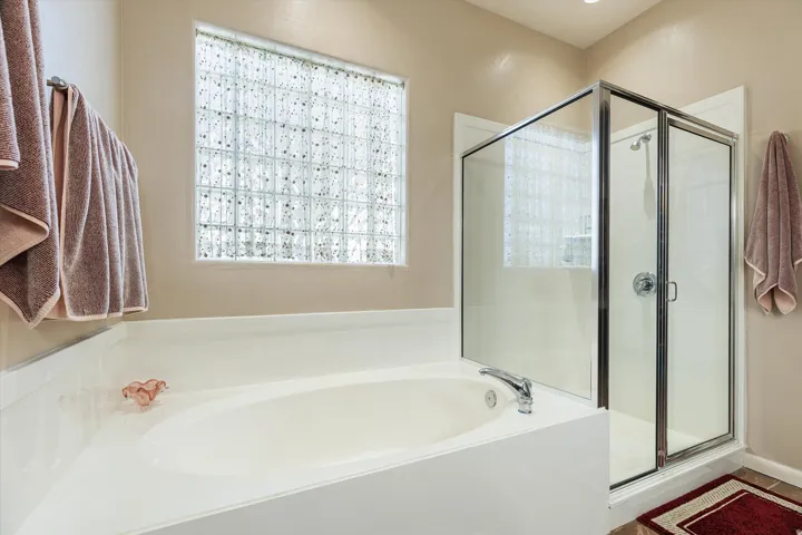 Soaking tub with deck-mounted faucet, glass block window, and separate shower enclosure
