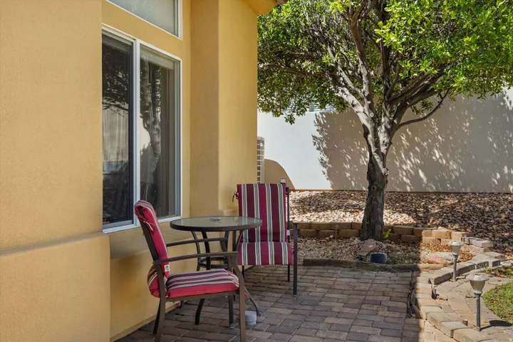 Stucco exterior with multiple pane windows, paver patio, mature tree, and decorative landscape lighting