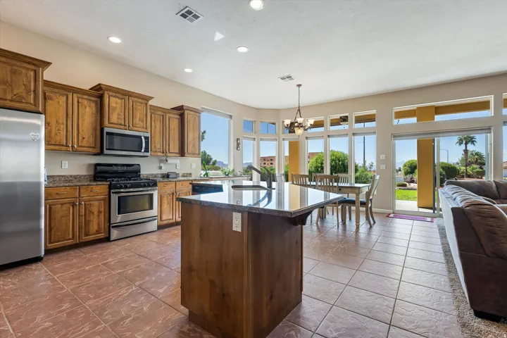 Kitchen featuring wood cabinetry, stainless steel appliances, a center island with a stone countertop, and tile flooring
