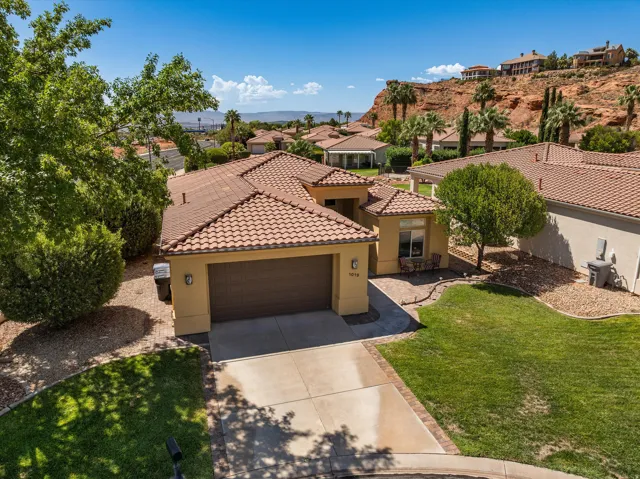 Single-story residence featuring a tile roof, an attached garage, a paved driveway, and a front patio area