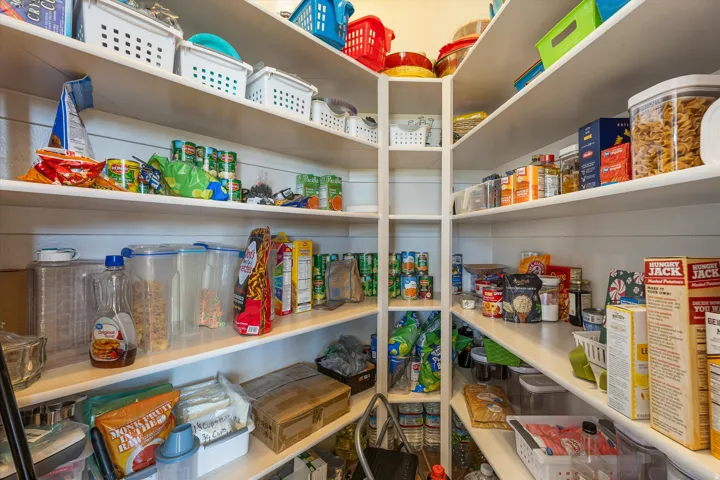 Expansive pantry with built-in shelving, ample storage capacity, and corner shelving design