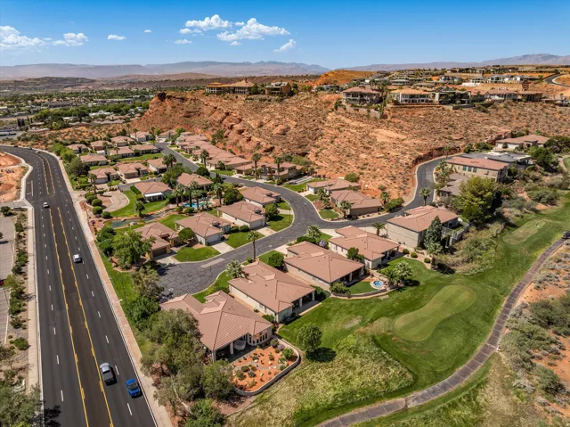 Residential area with paved roads, surrounding natural rock formations, and a golf course