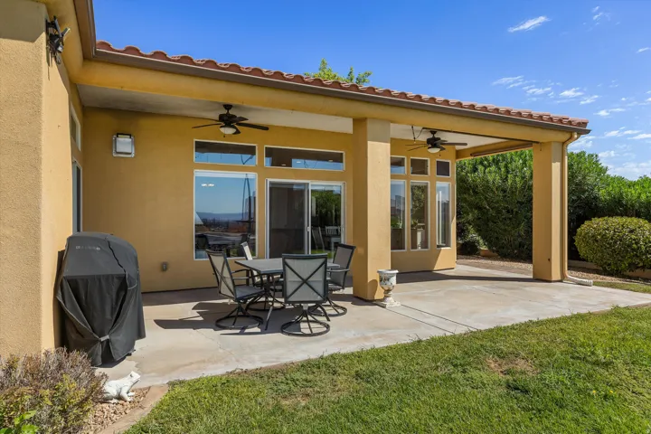 Covered patio featuring a tile roof, stucco exterior, ceiling fans, and a sliding glass door