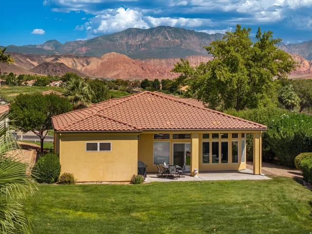 Stucco exterior with a terracotta tile roof, expansive lawn, and a concrete patio