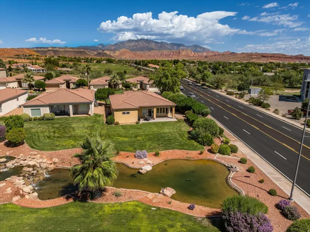 Terracotta roof tiles, stucco exterior, private patio, landscaped grounds with water feature, and mountain backdrop