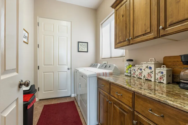 Warm wood cabinetry with brushed nickel hardware, expansive countertop space, and tile flooring