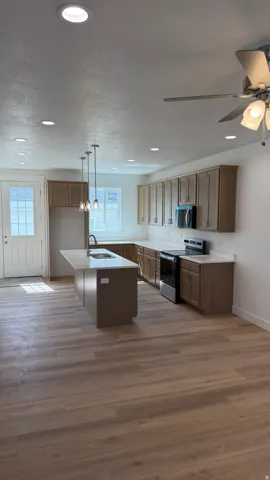 Open-concept kitchen featuring an island with breakfast bar, stainless steel appliances, recessed lighting, and wood-finish flooring