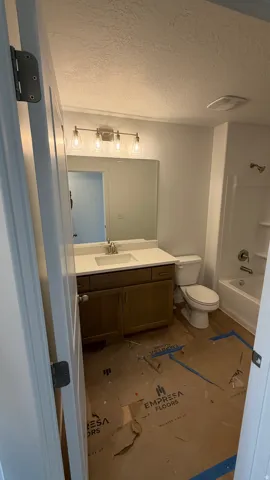 Bathroom featuring a vanity with a white countertop and undermount sink, a toilet, and a shower-tub combination