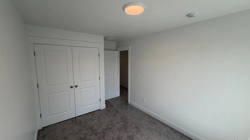 Plush carpet flooring, white painted walls, white trim, white paneled doors, and a flush mount ceiling light