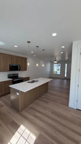 Gourmet kitchen with wood-finish flooring, recessed lighting, and a kitchen island featuring a double-basin sink and pendant lighting