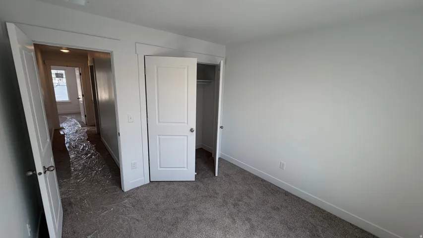 Neutral wall paint, carpeted flooring, white trim, and a white interior door