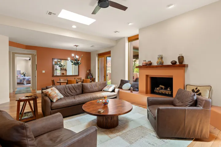 Hardwood flooring, ceiling fan, skylight, recessed lighting, and a fireplace with a wood mantle