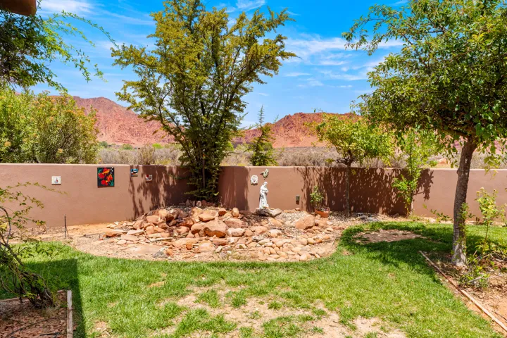 Backyard featuring a privacy wall, established trees, and a rock garden